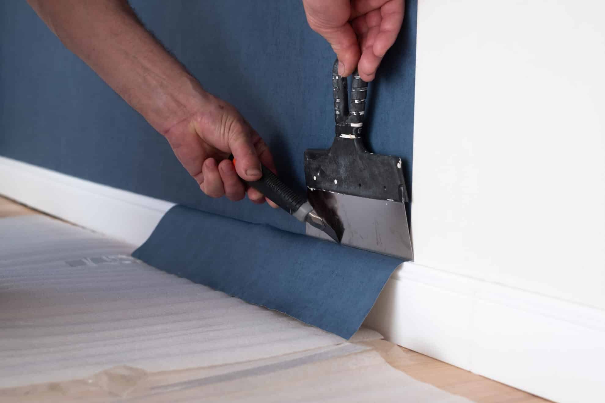 Man cutting wallpaper. Maintenance repair works renovation in the flat. Restoration indoors.